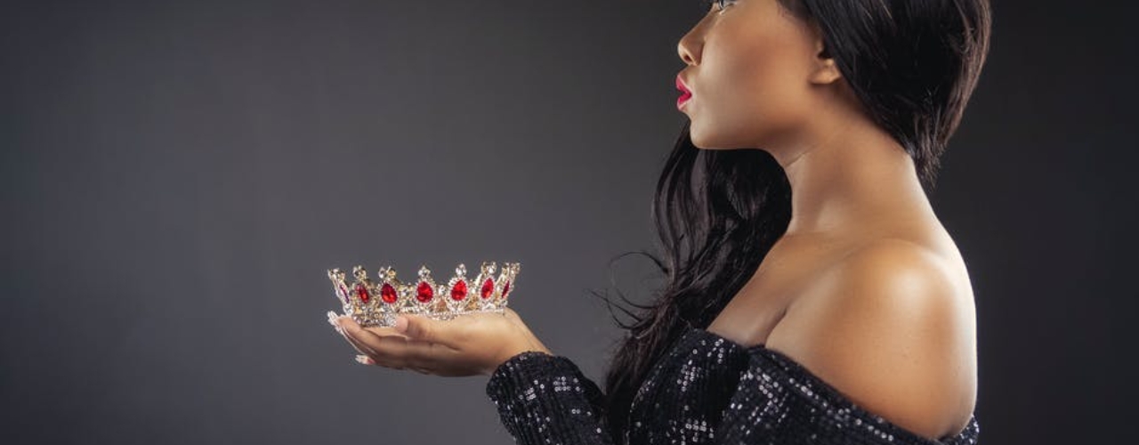 Beautiful young black woman holding crown in both hands
